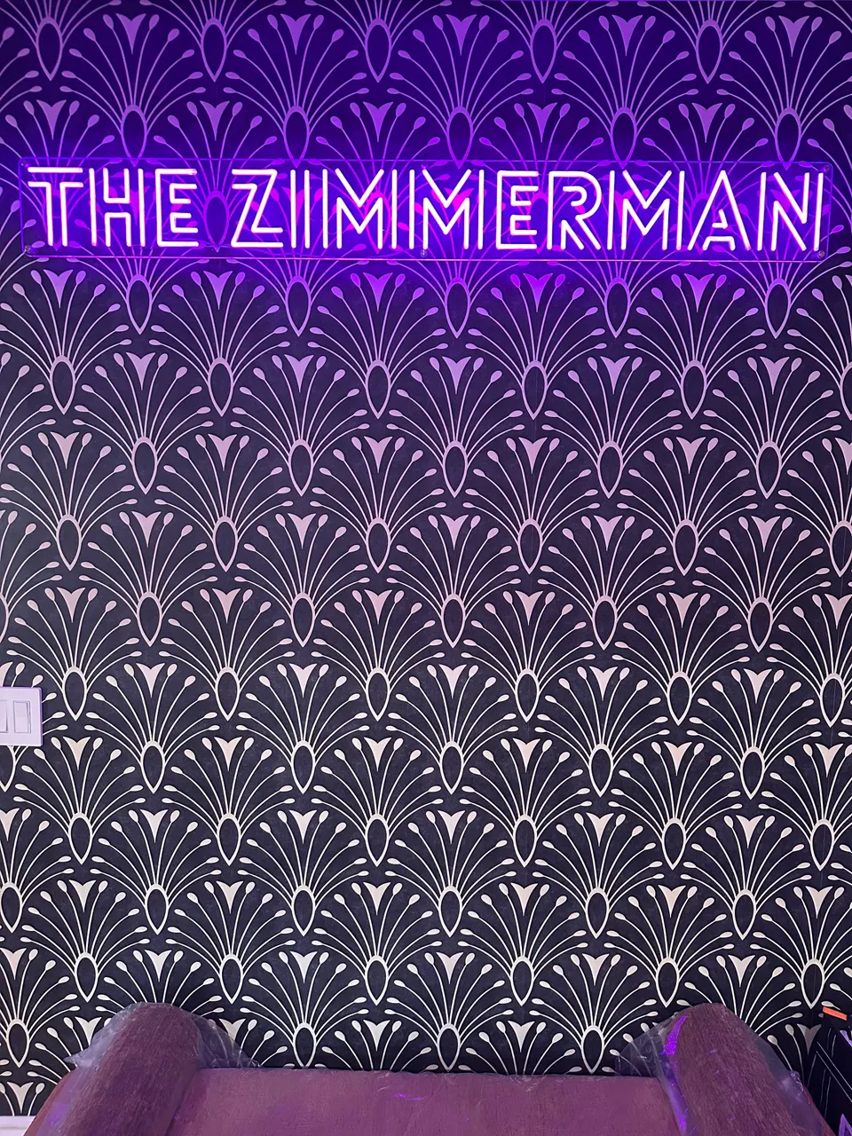 The Zimmerman, lit in purple neon over gold Art Deco fan wallpaper