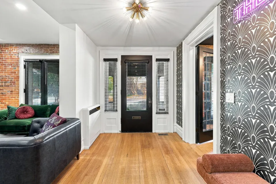 The front door from the hall, between the brick wall and the fan wallpaper