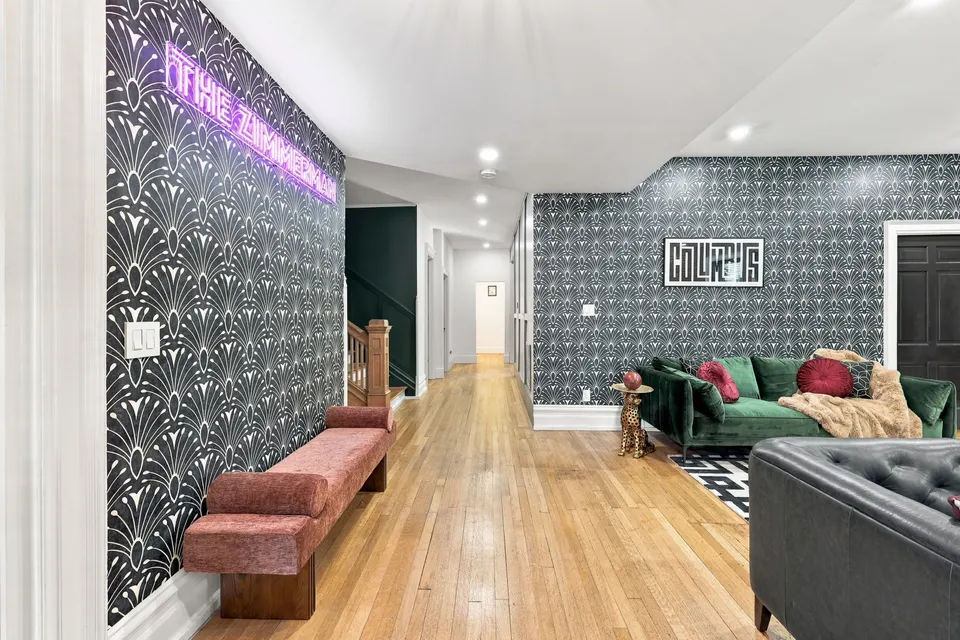 The entrance hall under the purple neon sign, with the living room beyond