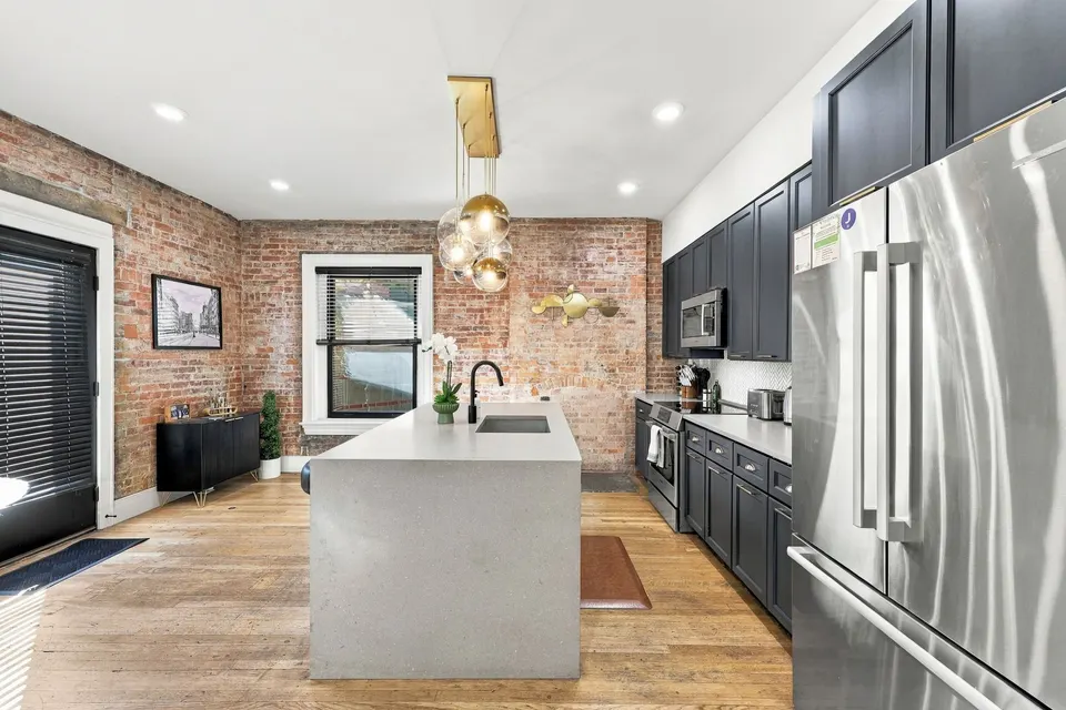 The kitchen: marble island, brass pendants and the original brick