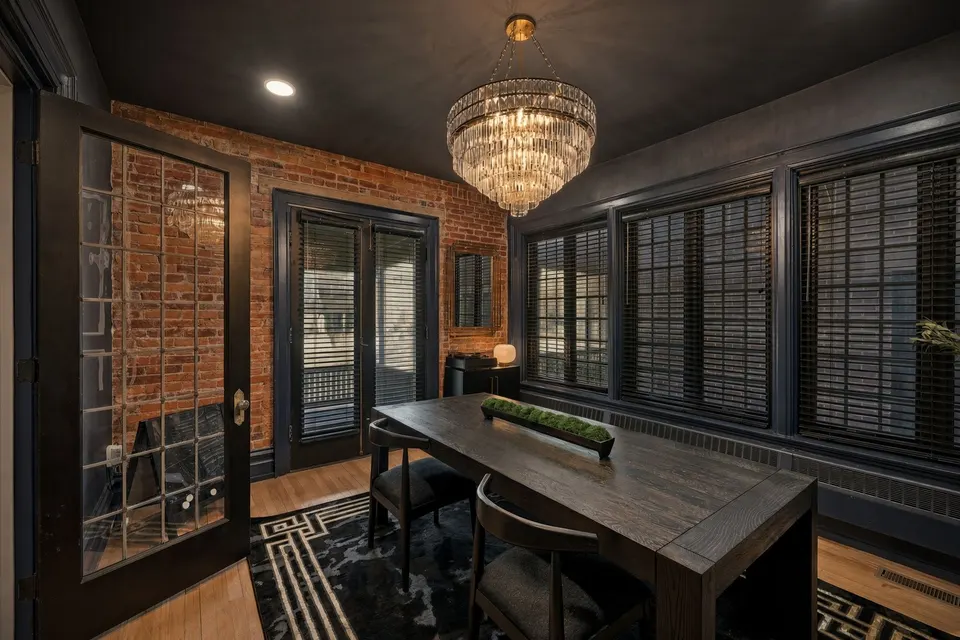 The office: a long table under a crystal chandelier, between brick walls